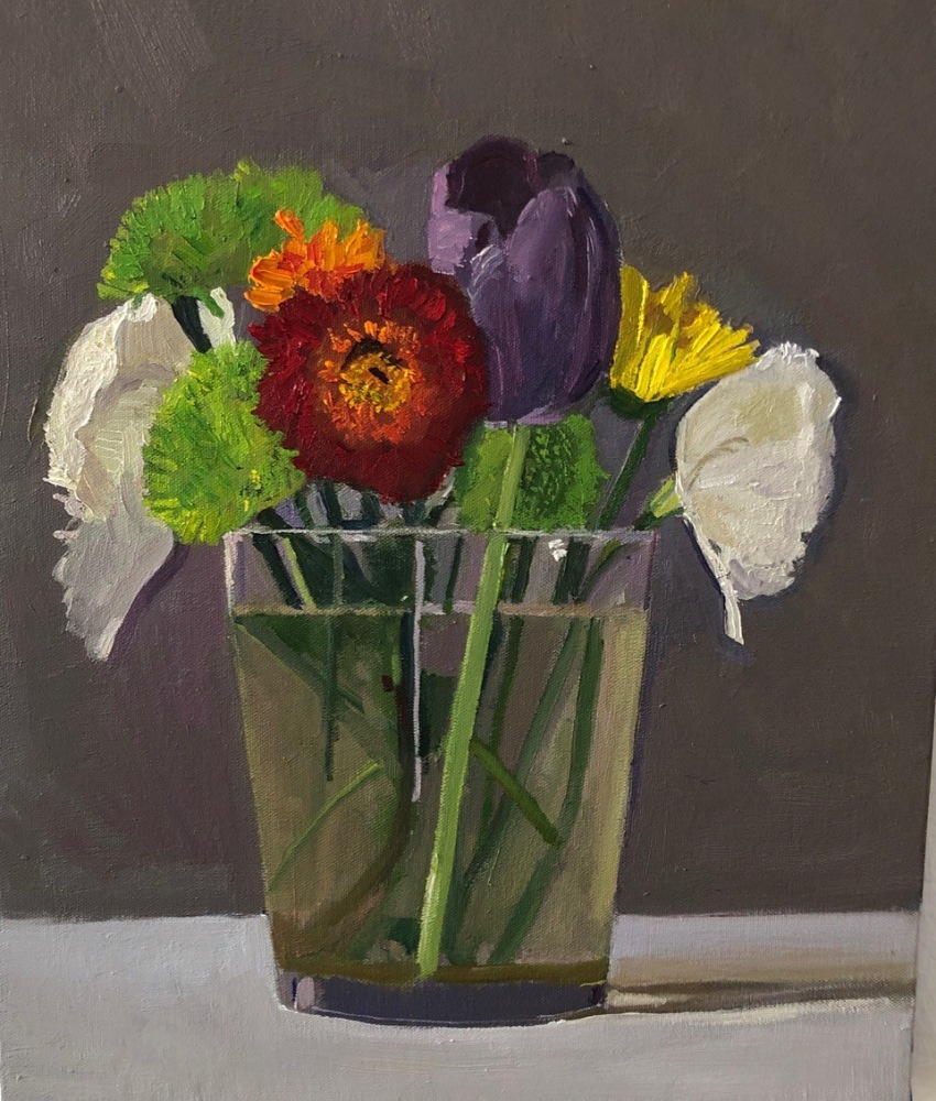 mixed bouquet of flowers including a purple tulip in a glass vase