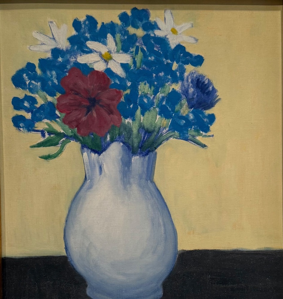 white vase with flowers and a red petunia on a brown table with a soft yellow background