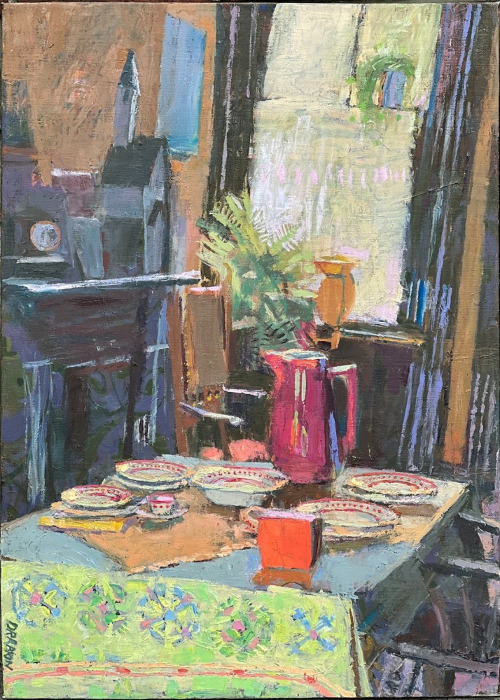 interior with green tablecloth with red plates and a red vase with flowers and a window in the background