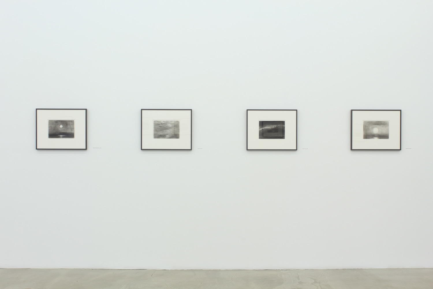 Photograph of four framed drawings on a white wall