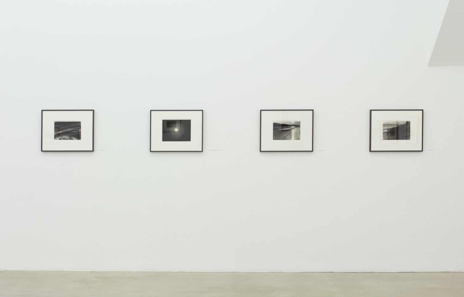 Photograph of four framed drawings on a white wall