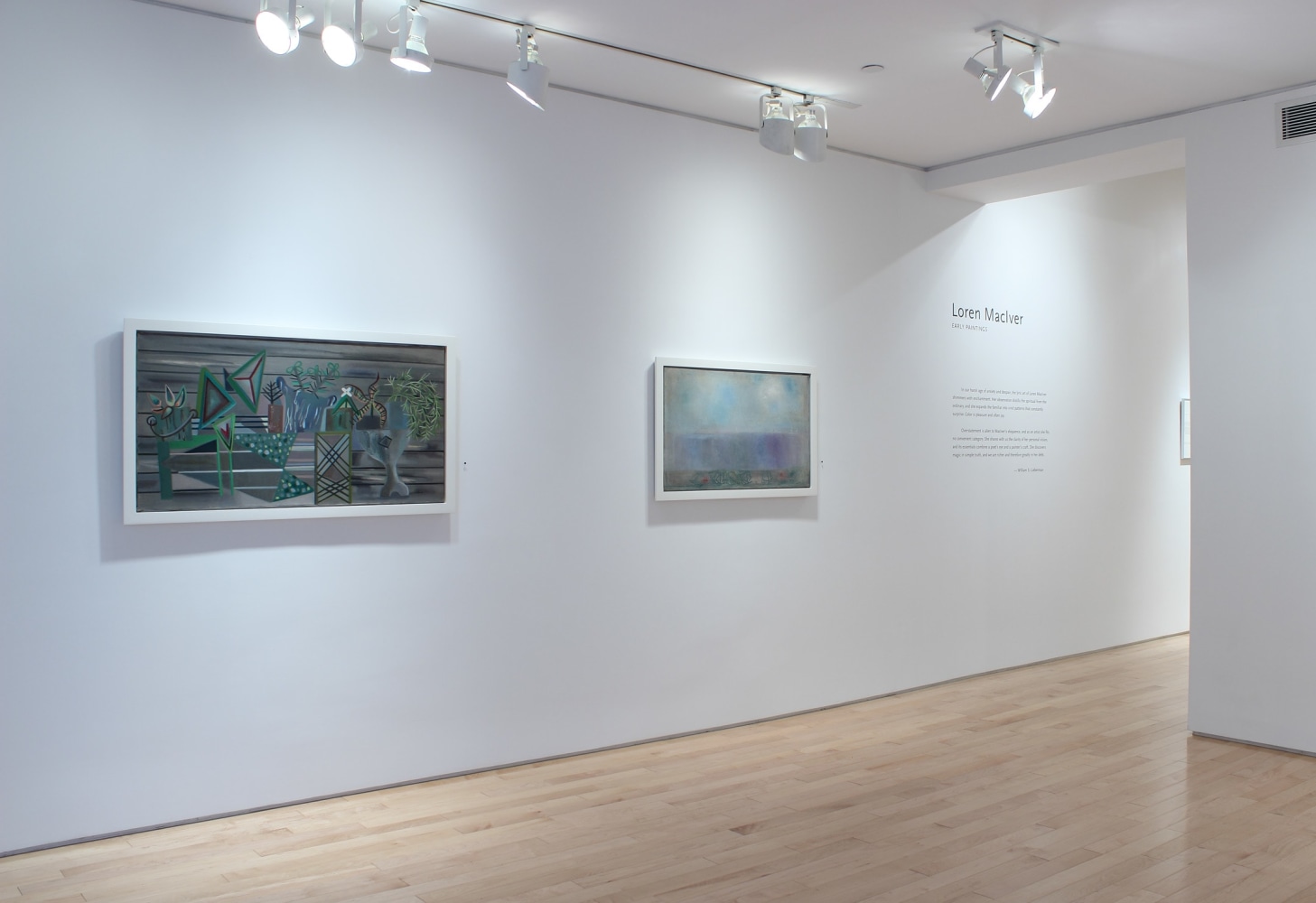 Photograph showing a view of an exhibition with two paintings hanging on a white wall, with wall text describing the exhibition to the right