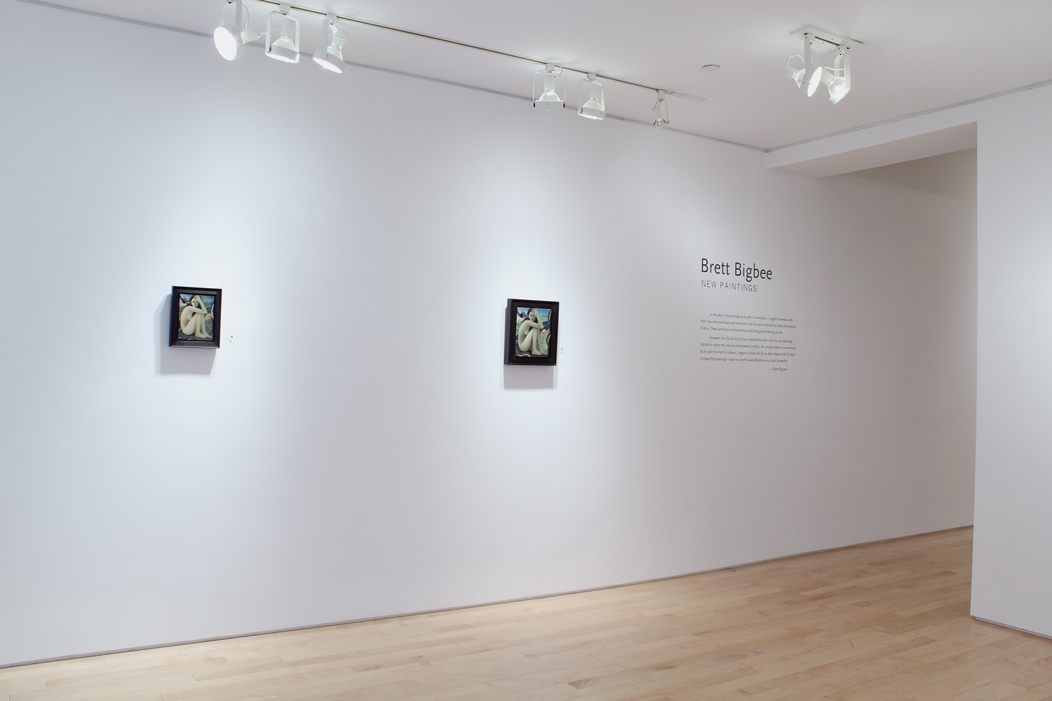 Photograph showing a view of an exhibition with two small paintings hanging on a white wall