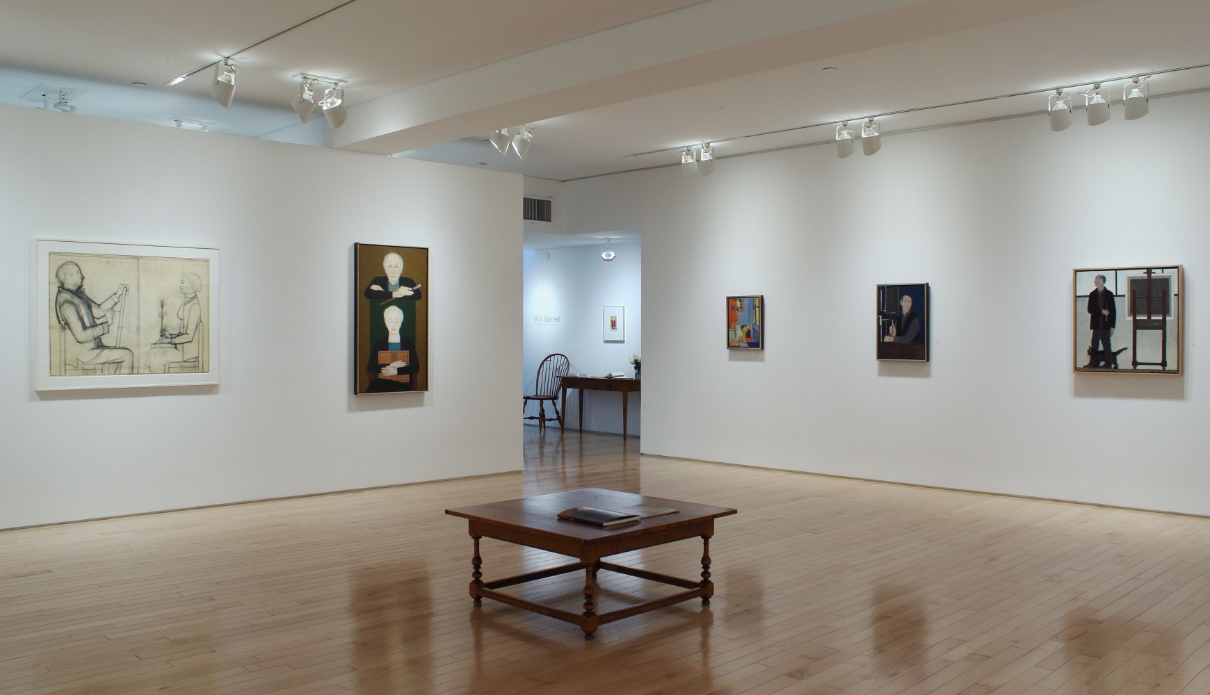 Photograph showing a corner view of an exhibition space, with five paintings hung on white walls
