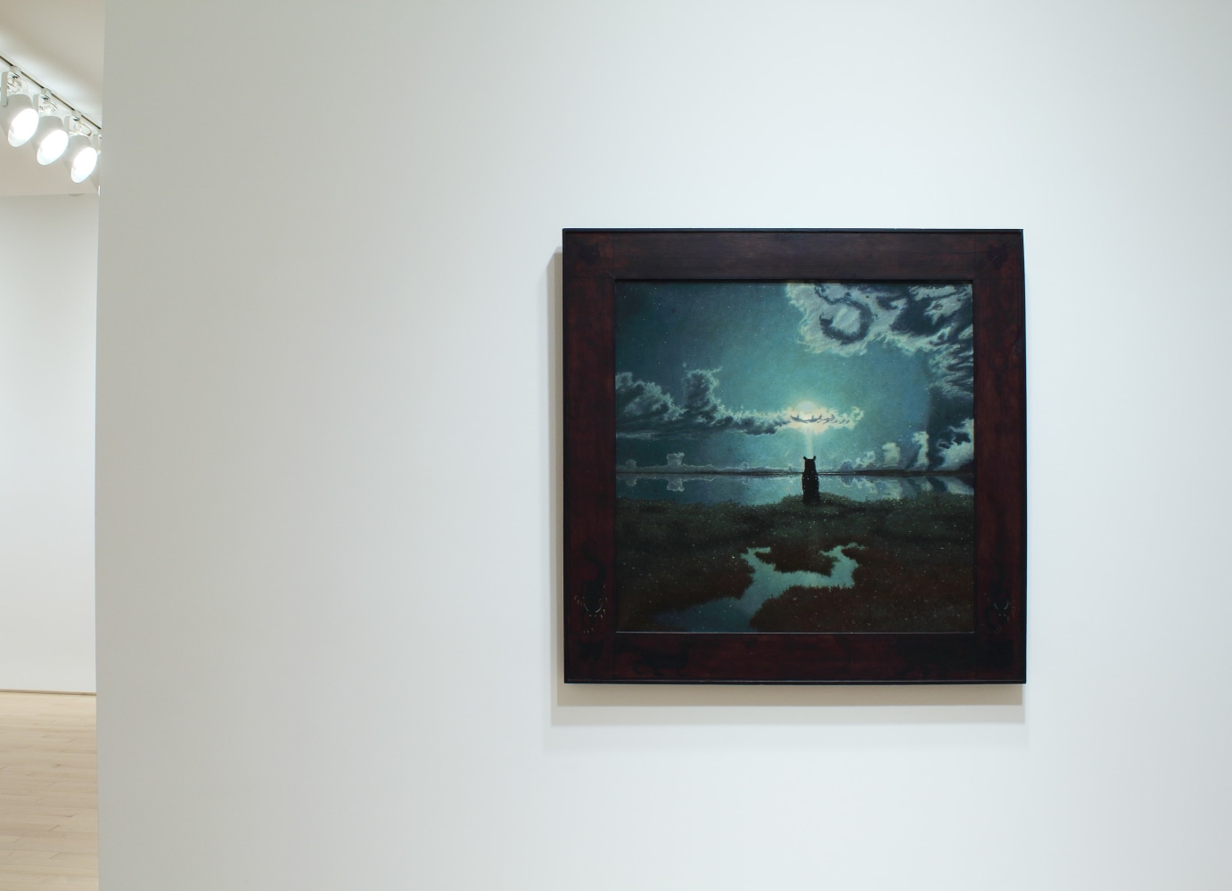 Photograph showing a view of an exhibition space, with one small painting hung on a white wall