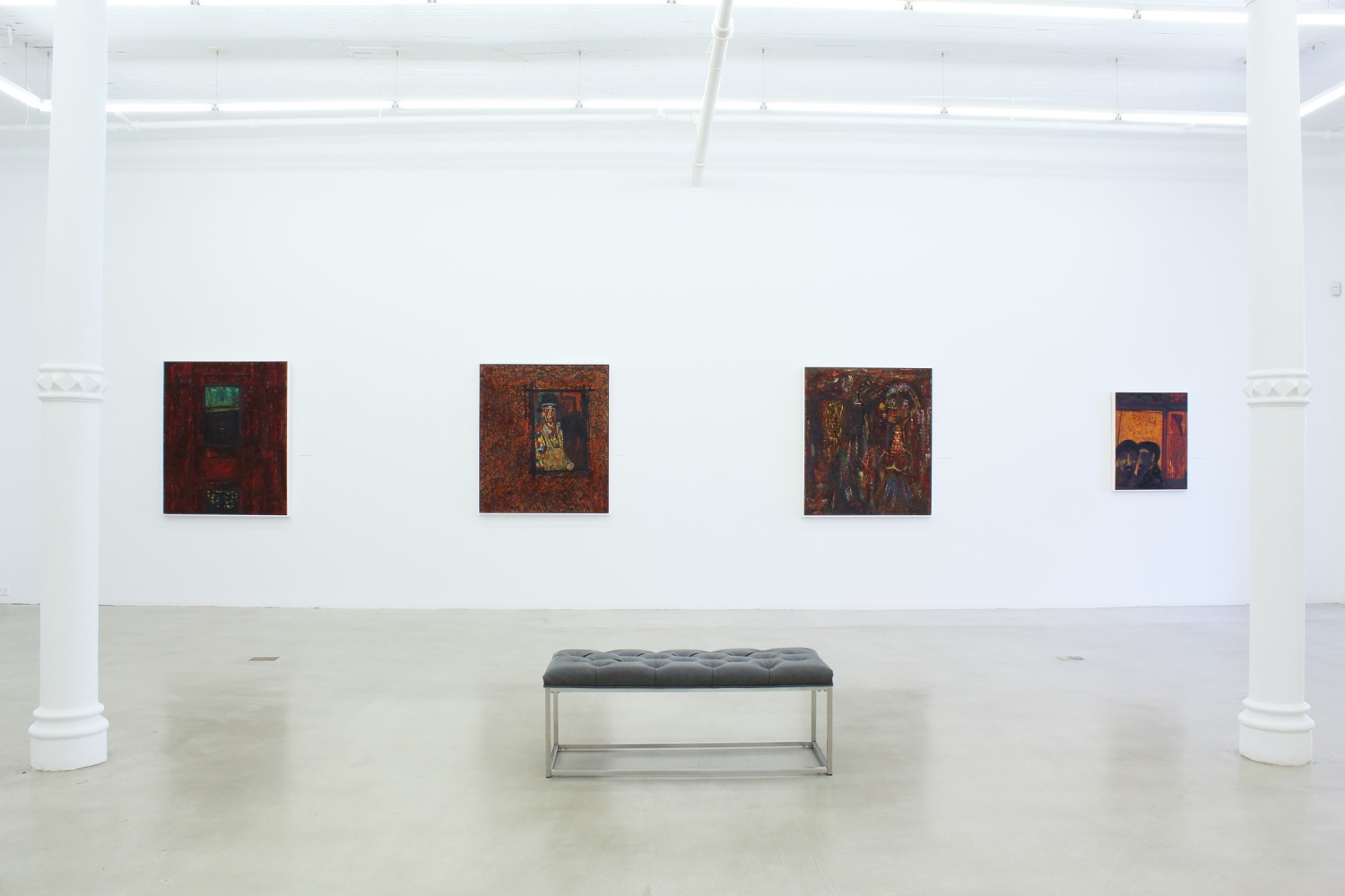 Photograph showing a view of an exhibition space, with four paintings hanging on a white wall
