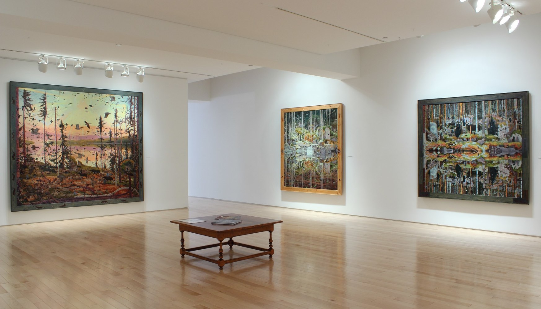 Photograph showing a corner view of an exhibition space, with three paintings hanging on white walls