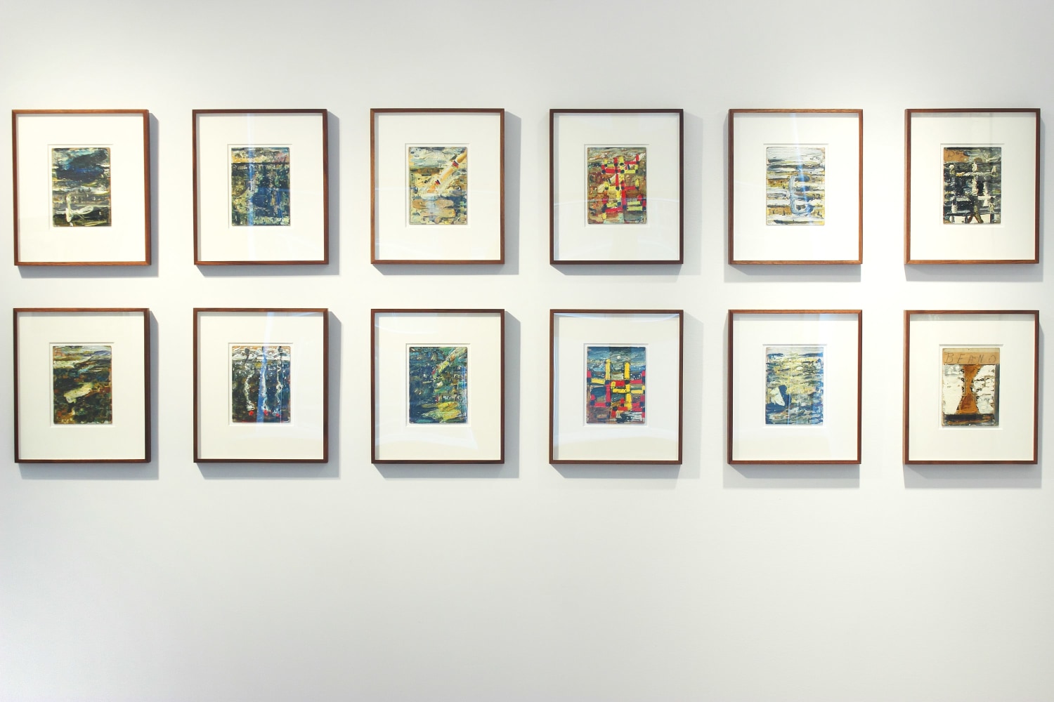 Photograph showing a view of an exhibition space, with twelve small framed drawings hanging on a white wall