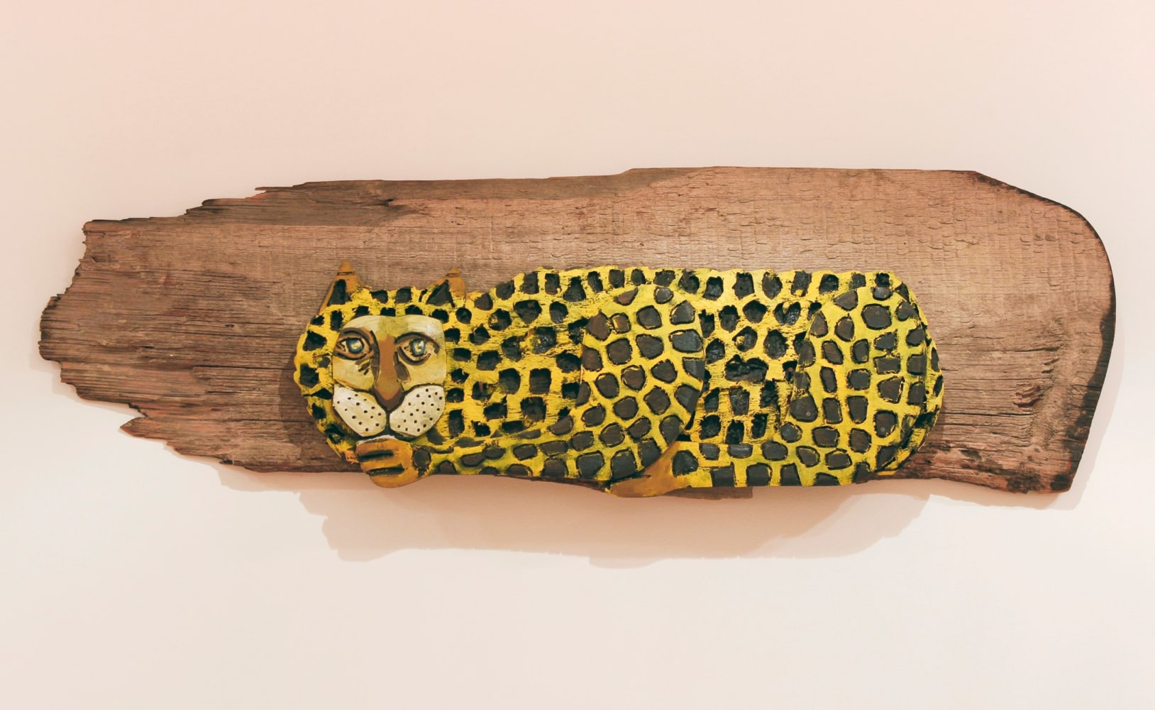 Wall-hanging, partially-painted wood sculpture of an abstracted leopard