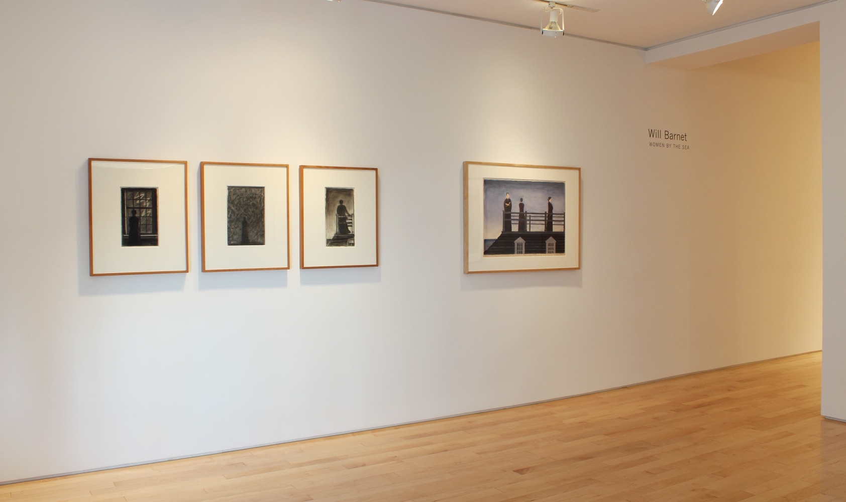 Photograph showing a view of an exhibition space, with four framed drawings hanging on a white wall
