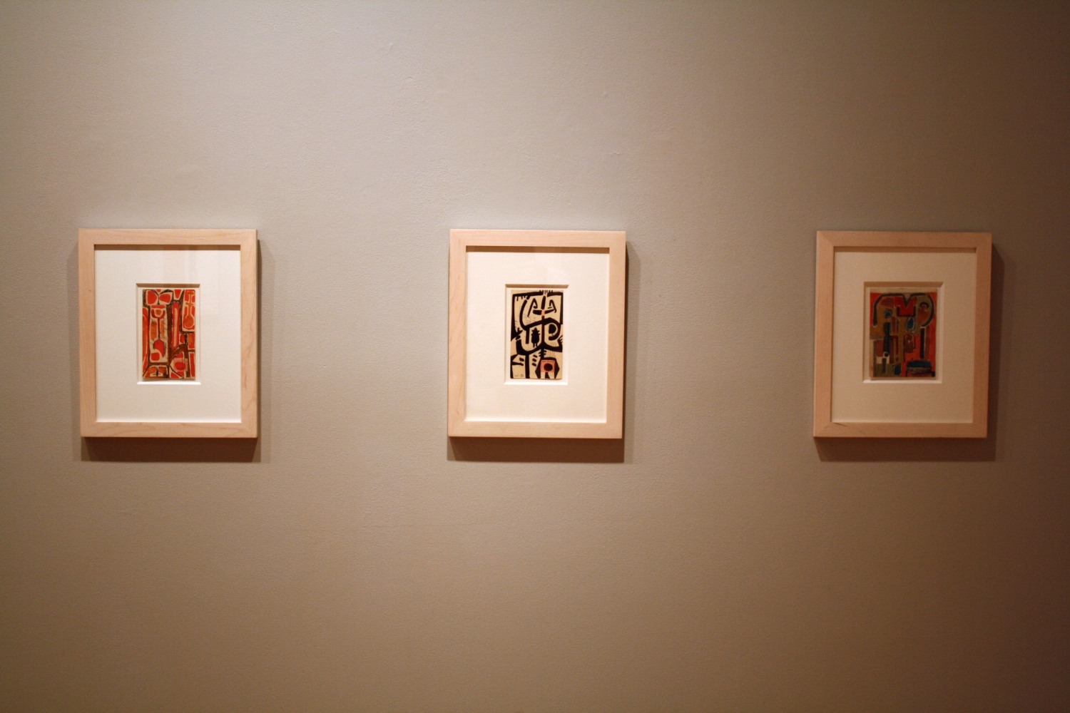 Photograph showing a view of an exhibition, with two small framed drawings hanging on a grey wall