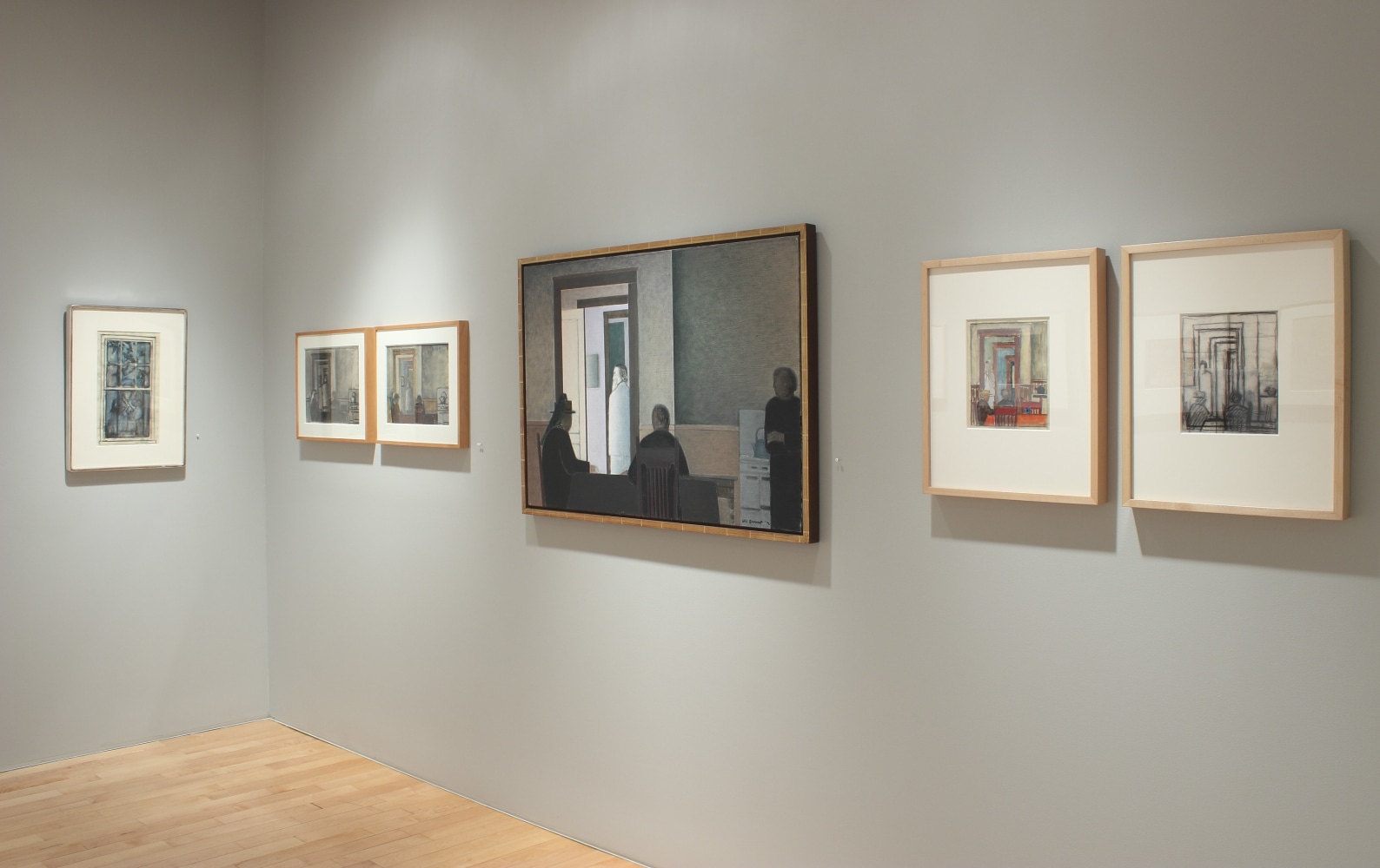 Photograph showing a corner view of an exhibition space with one painting and five framed drawings hanging on two walls
