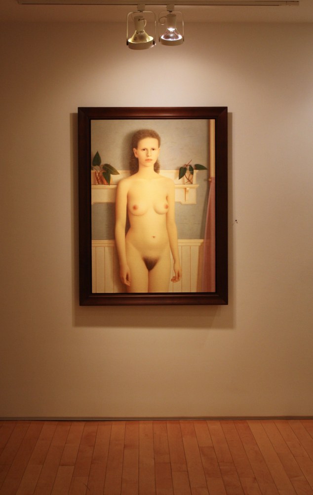 Photograph showing a view of an exhibition, with one framed painting hanging on the wall