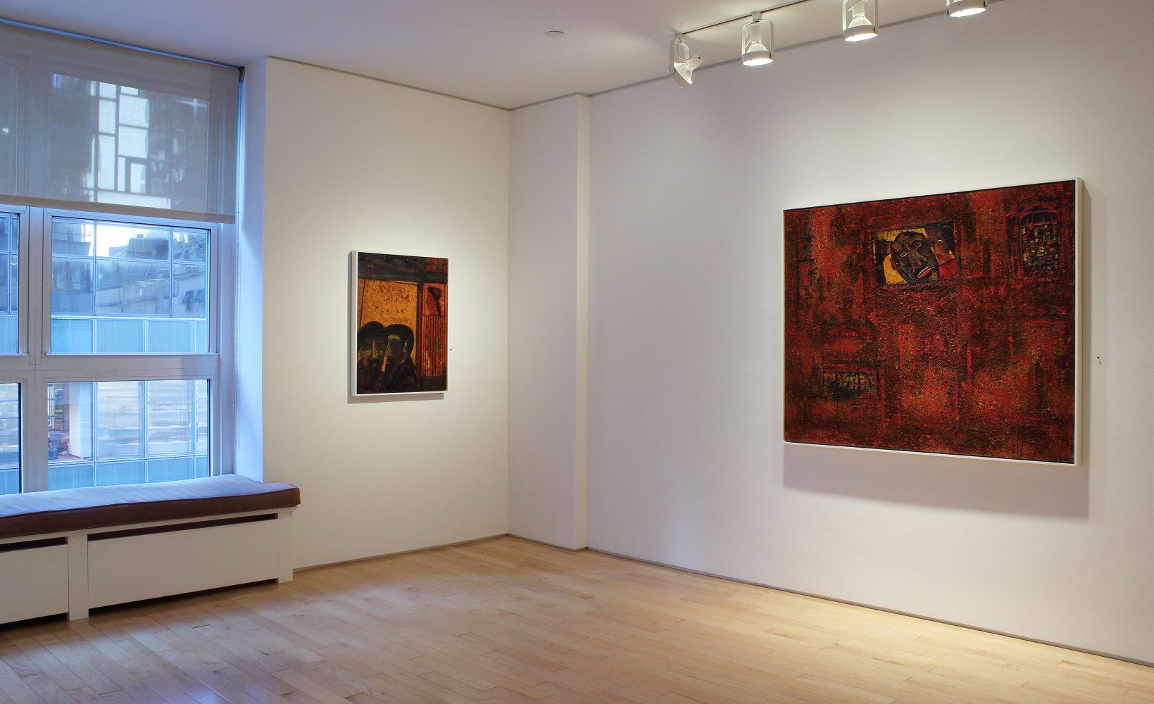 Photograph showing a corner view of an exhibition space, with two paintings hung on white walls