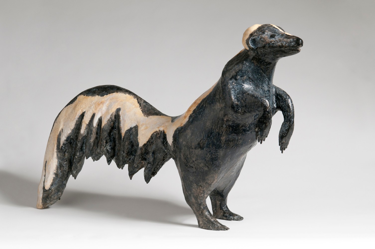 Side view of a sculpture of a skunk standing on its hind legs