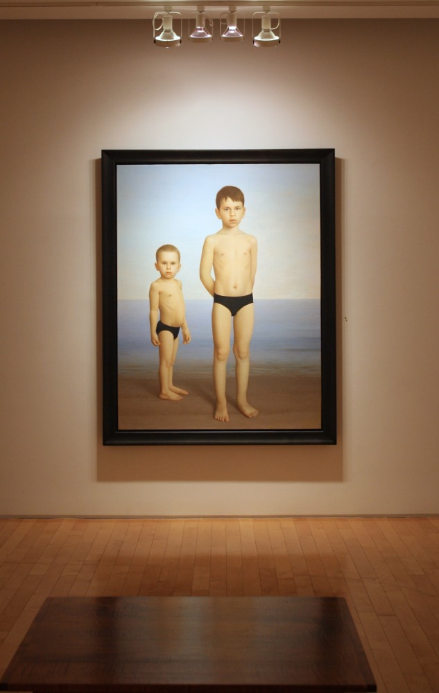 Photograph showing a view of an exhibition, with one large framed painting hanging on a white wall