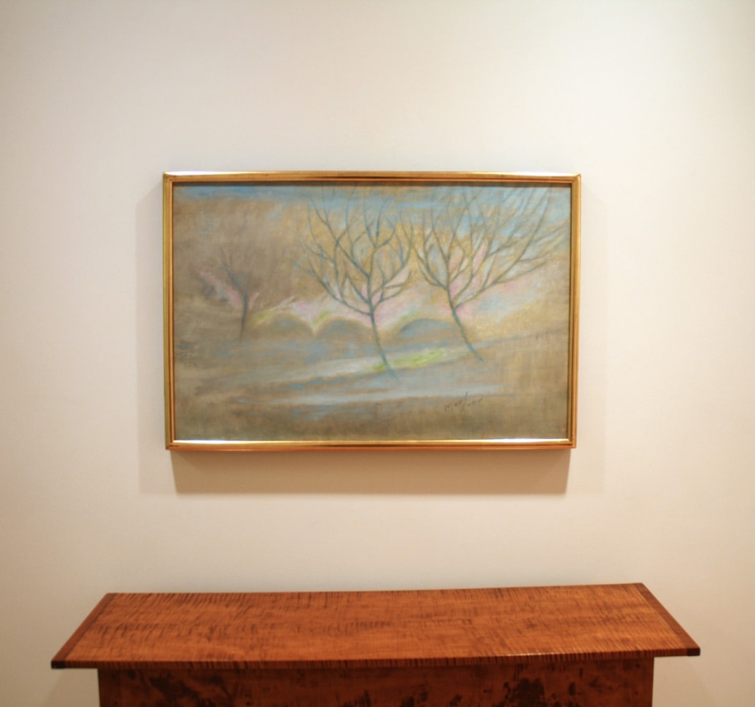 Photograph showing a view of an exhibition, with one framed painting hanging over a wooden table