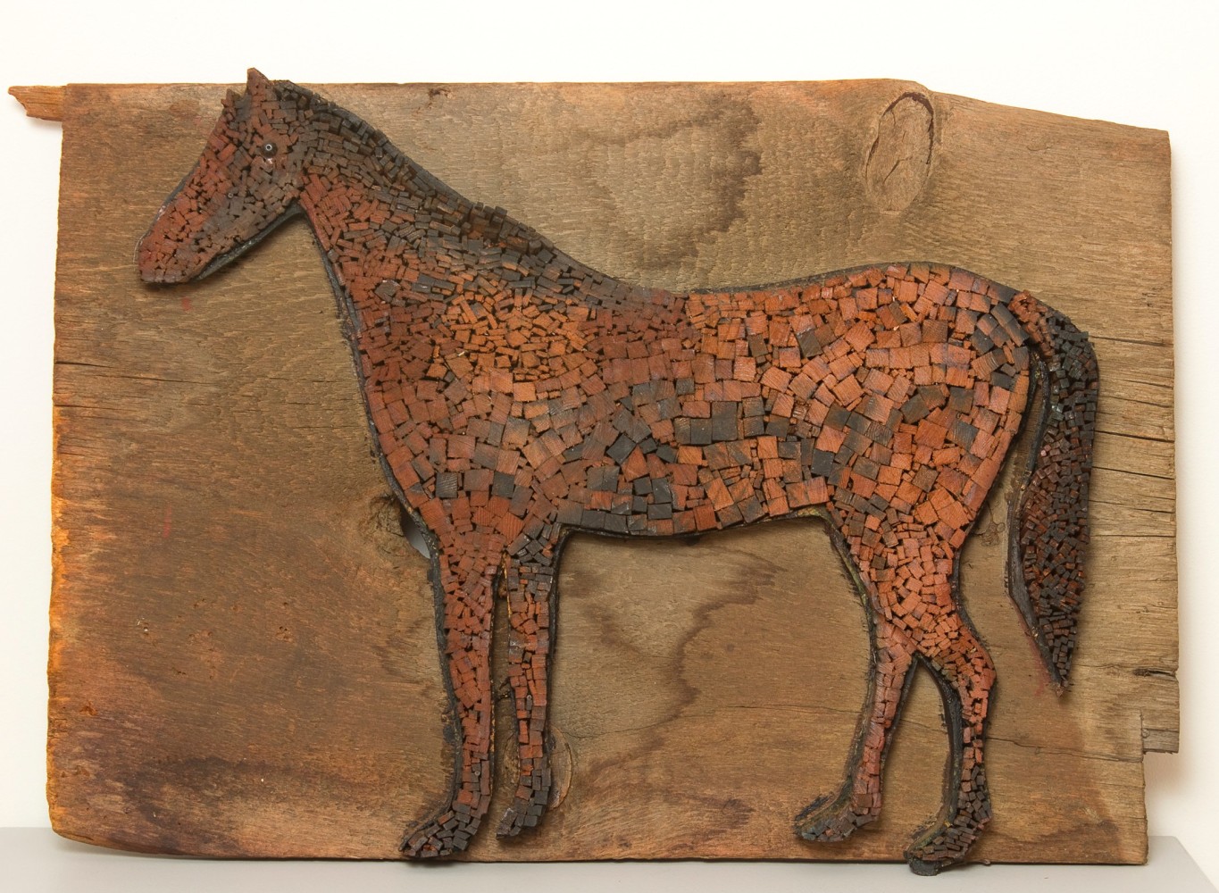 Wall-hanging sculpture of the figure of a horse composed of various pieces of wood