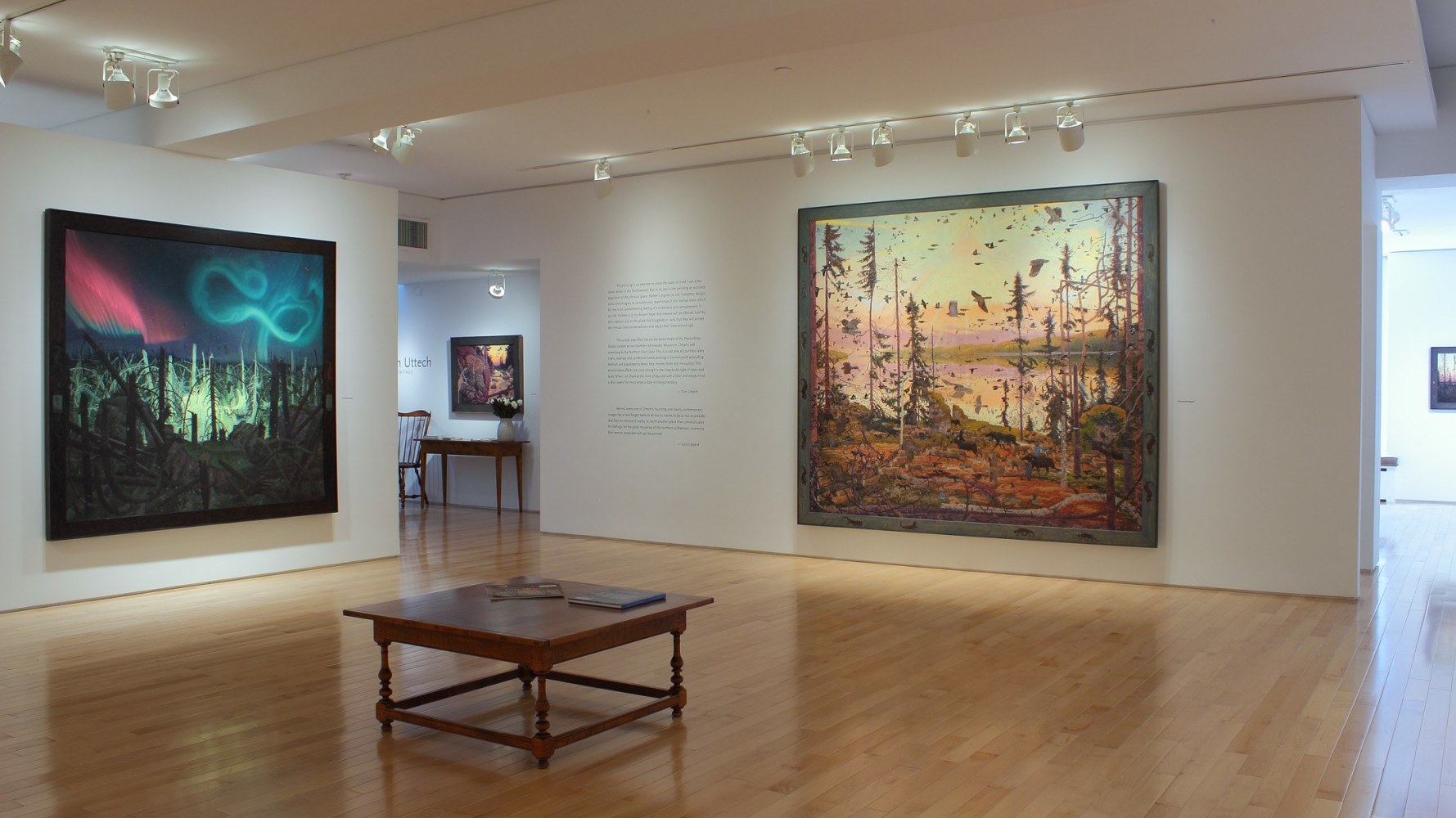 Photograph showing a corner view of an exhibition space, with three paintings hanging on white walls