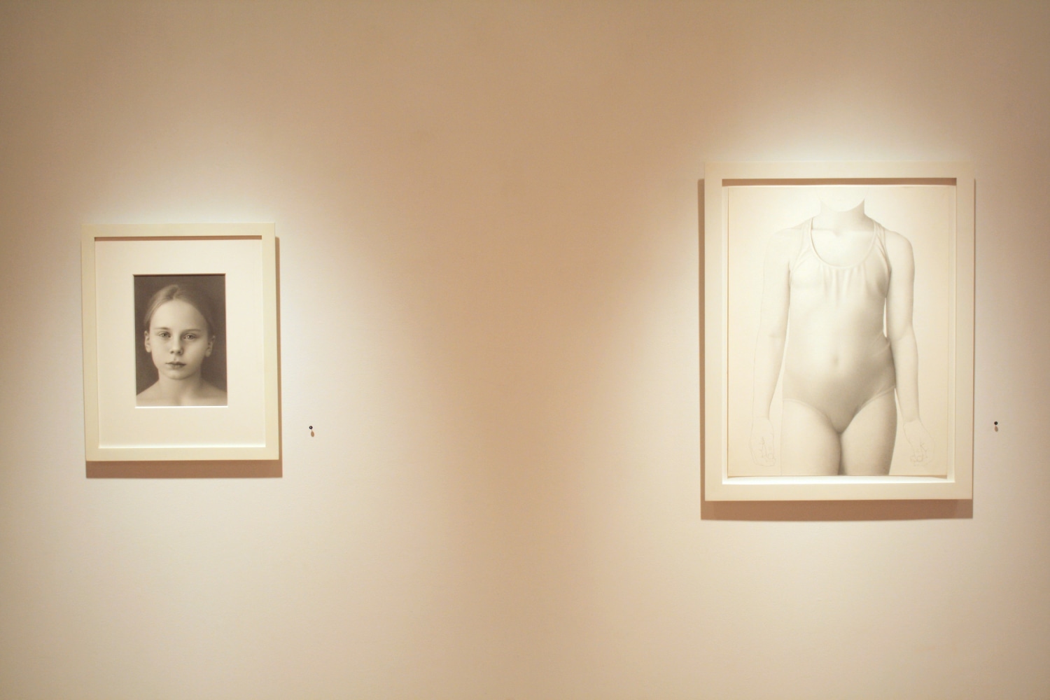 Photograph showing a view of an exhibition space, with two small framed drawings hanging on a white wall