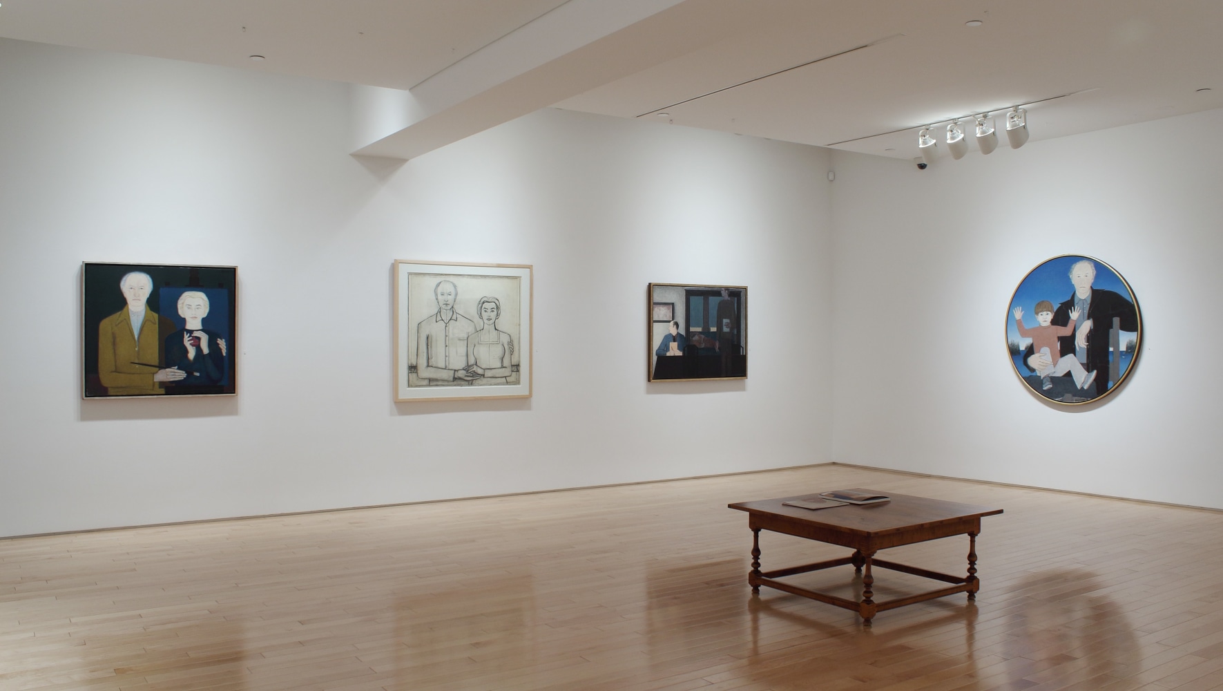 Photograph showing a corner view of an exhibition space, with four paintings hanging on white walls
