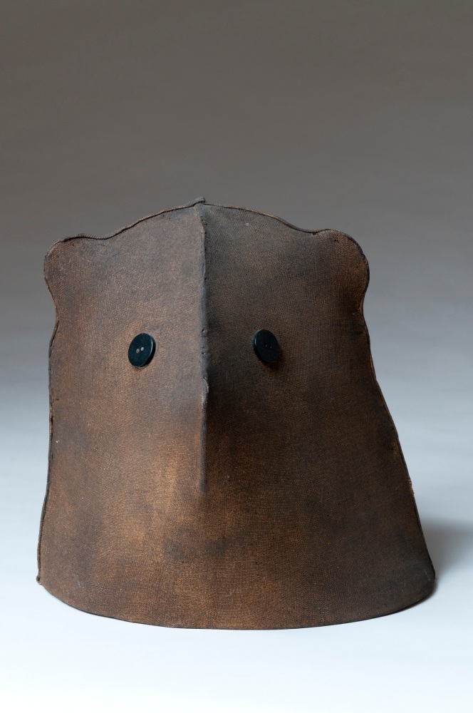Sculpture of an abstracted cat head from the neck up, with two black buttons in place of eyes