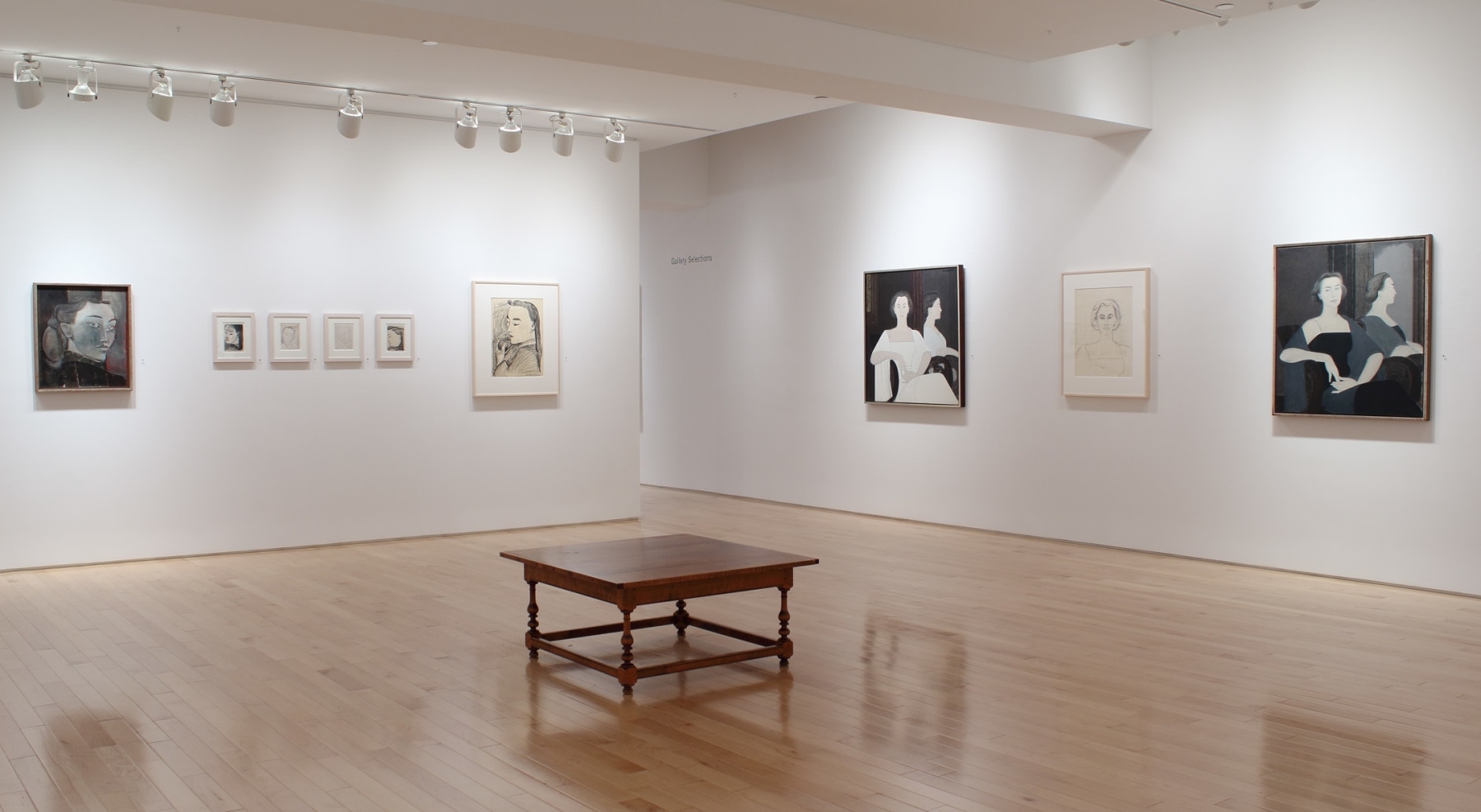Photograph showing a corner view of an exhibition space, with nine paintings hung on white walls