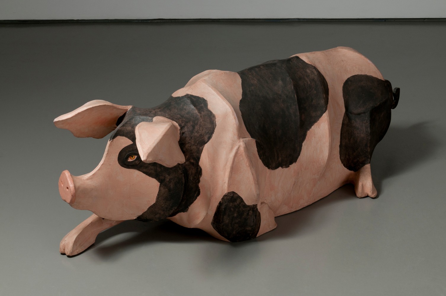 Sculpture of a pink pig with black spots, reclining