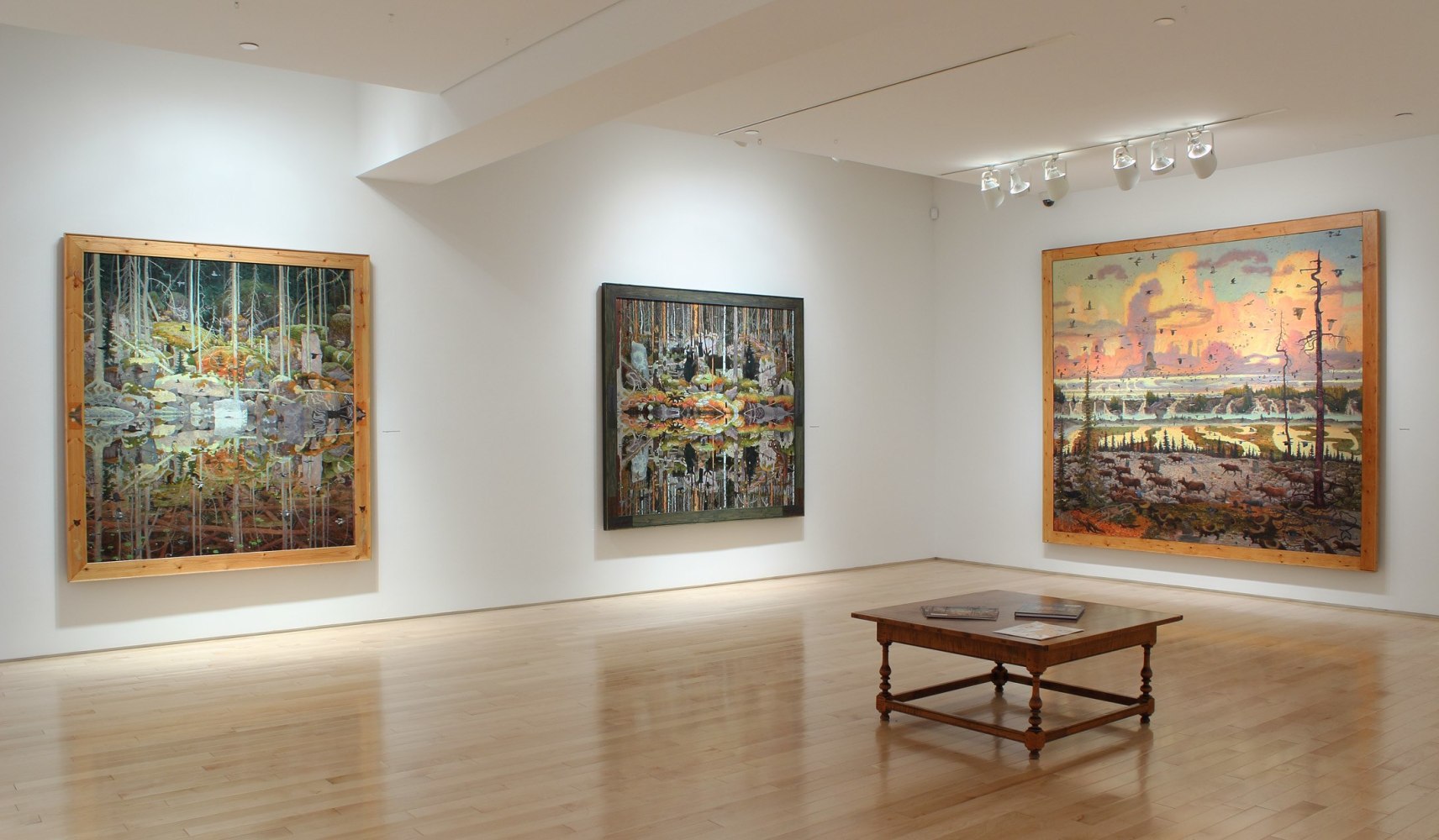 Photograph showing a corner view of an exhibition space, with three paintings hanging on white walls