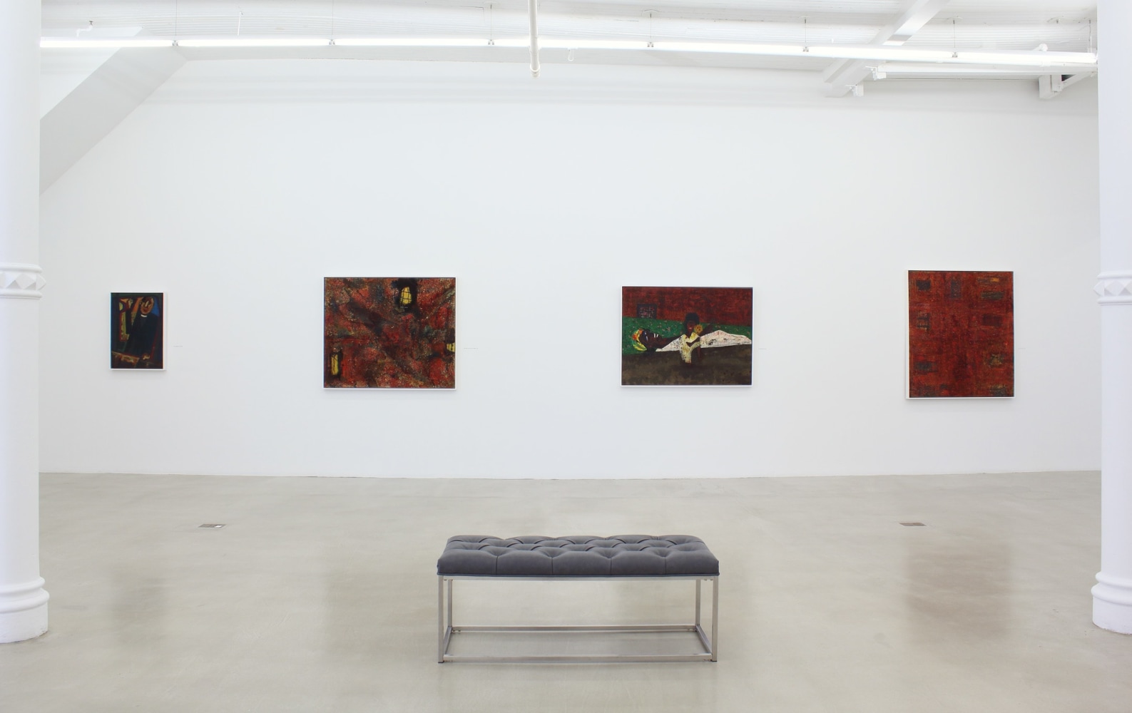 Photograph showing a view of an exhibition space, with four paintings hanging on a white wall