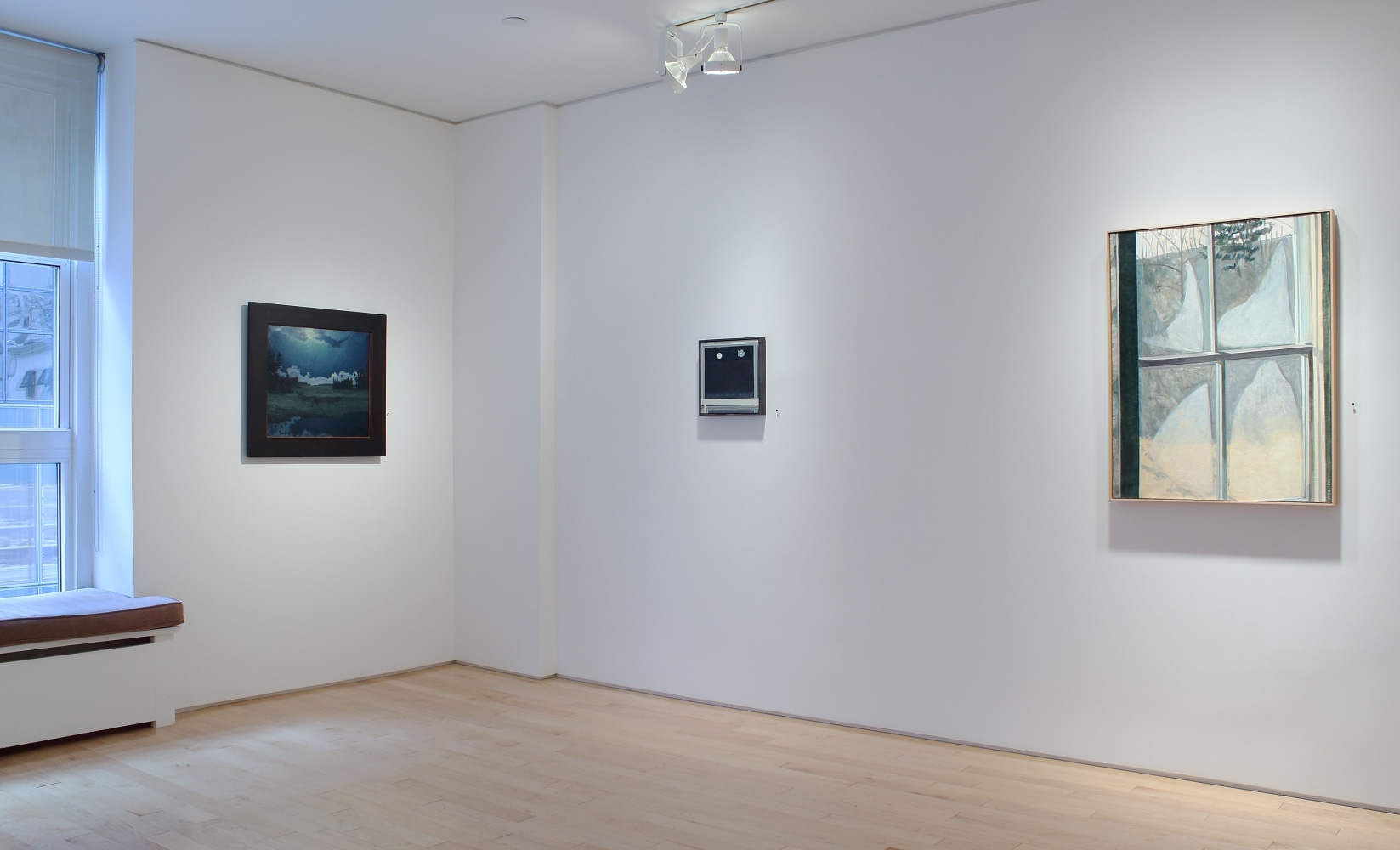 Photograph showing a corner view of an exhibition space, with three paintings hanging on white walls