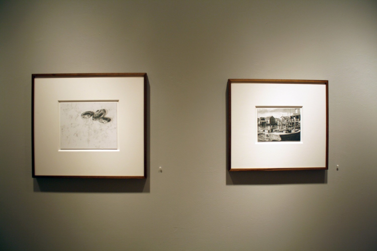 Photograph showing a view of an exhibition, with two small framed drawings hanging on a grey wall