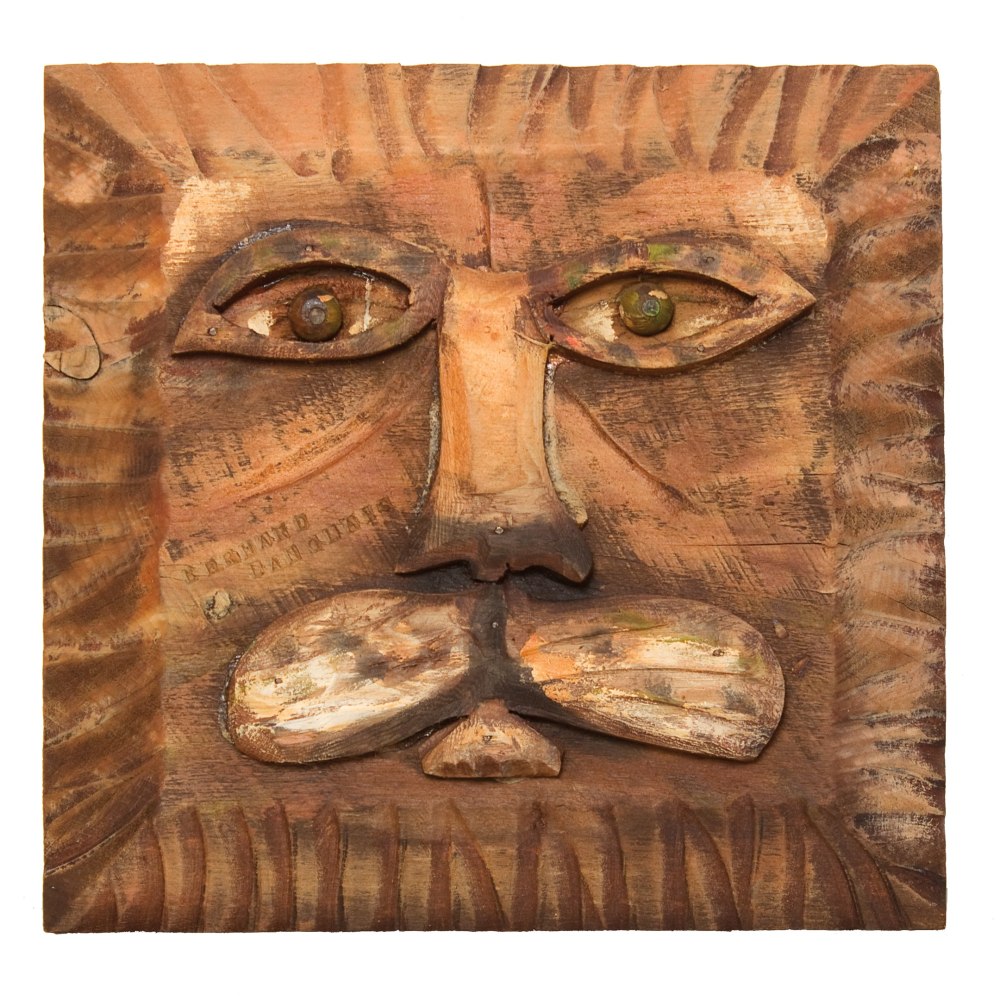 Painted wall-hanging wood sculpture of an abstracted lion's face