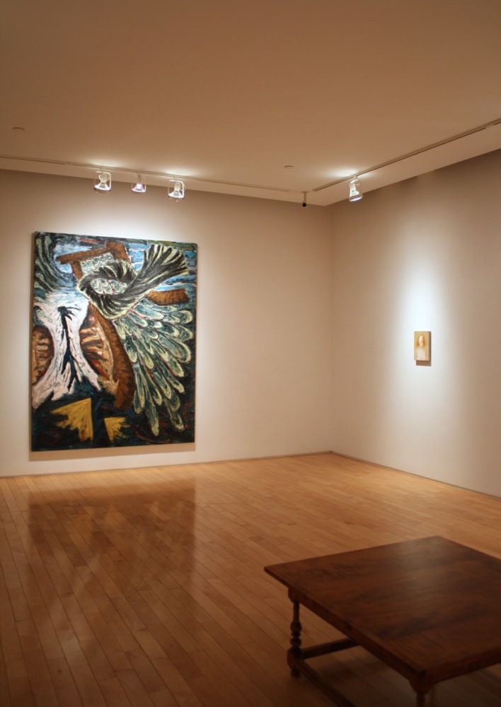 Photograph showing a corner view of an exhibition space, with one large painting and one small framed painting hanging on white walls