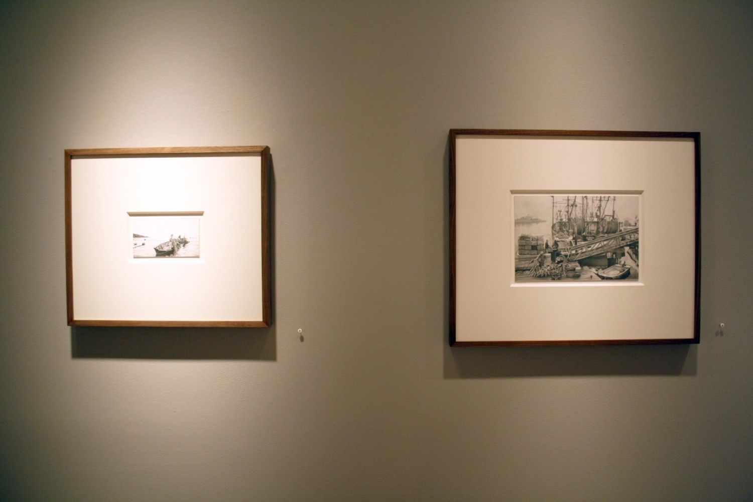 Photograph showing a view of an exhibition, with two small framed drawings hanging on a grey wall