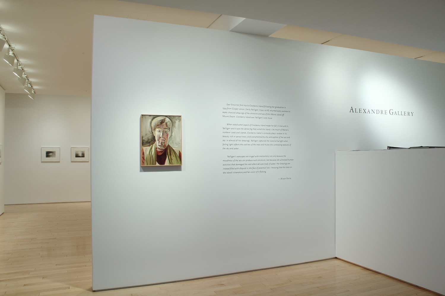 Photograph showing a front view of an exhibition space, with one painting hung on a white wall beside a block of wall text