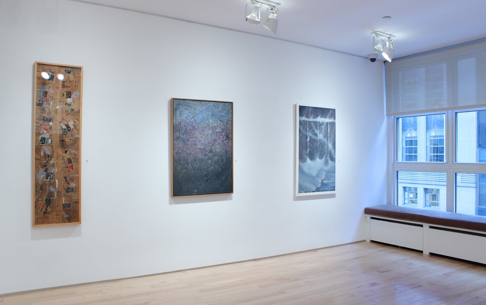 Photograph showing view of an exhibition space with three paintings hanging on a white wall