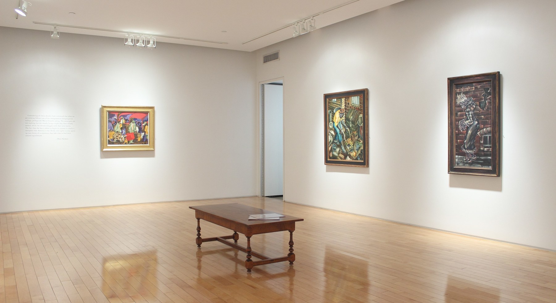 Photograph showing a corner view of an exhibition space, with three paintings hanging on white walls
