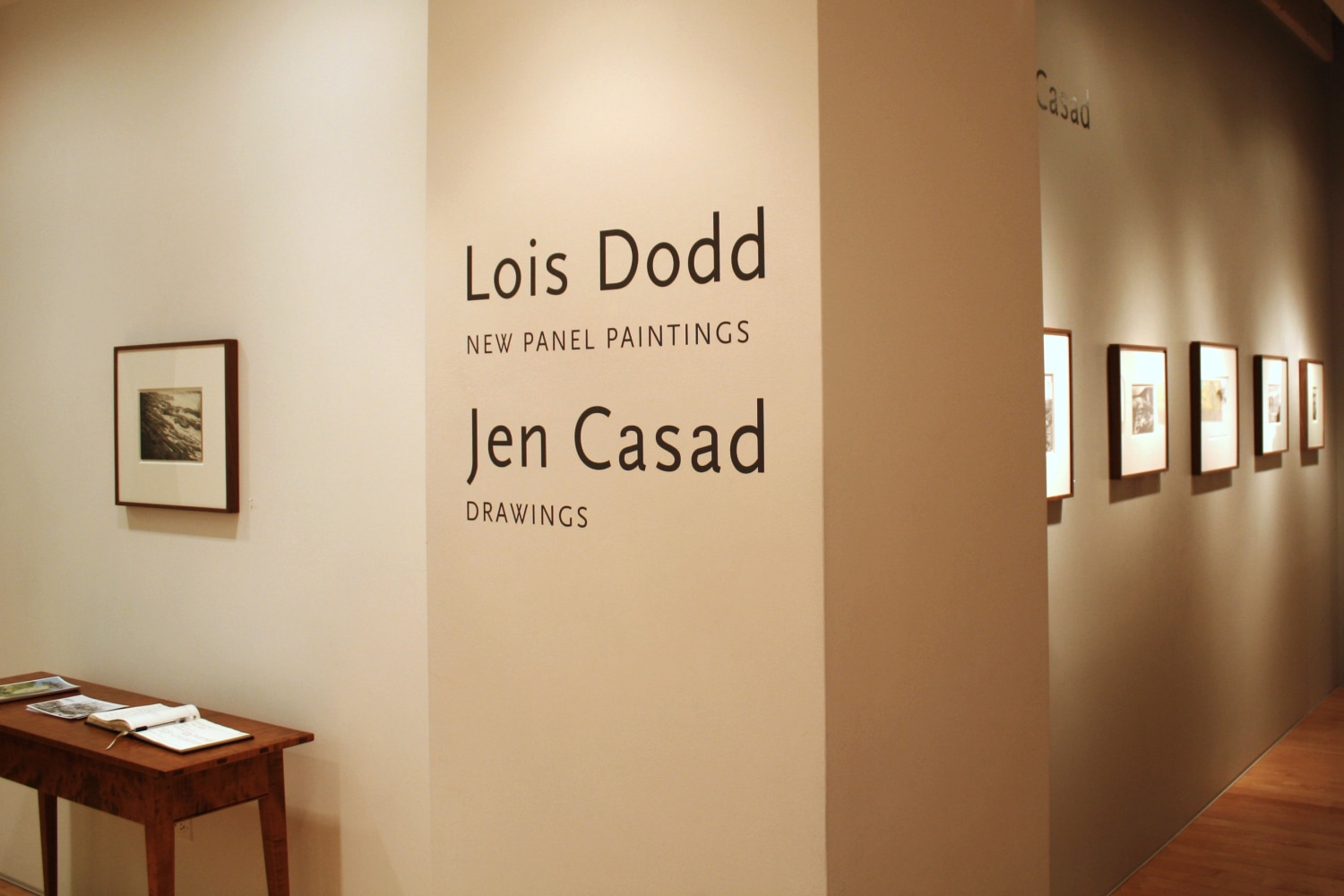 Photograph showing a view of an exhibition space, with six small framed drawings on the walls and wall text that reads &quot;Lois Dodd: New Panel Paintings,&quot; and &quot;Jen Casad: Drawings&quot; on the wall in the center
