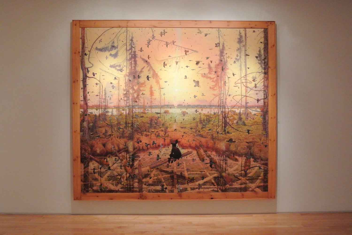 Photograph showing a view of an exhibition, with one large framed painting hanging on a wall