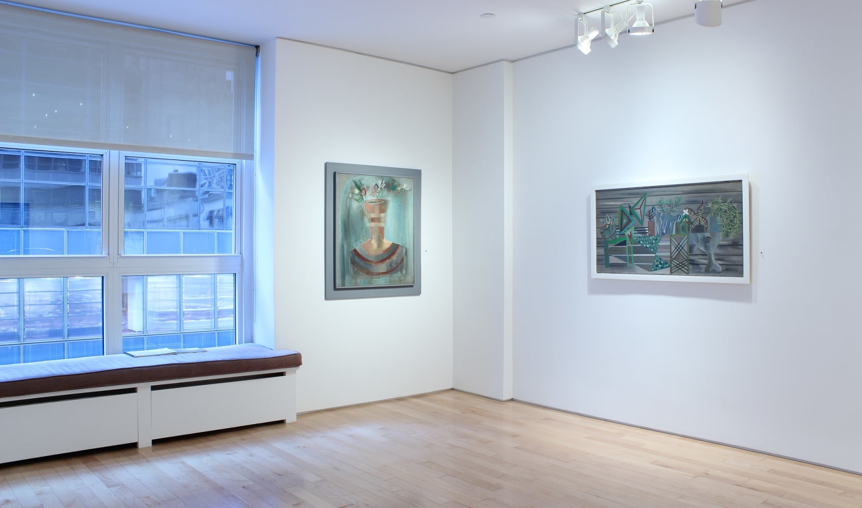 Photograph showing a corner view of an exhibition space, with two paintings hanging on white walls