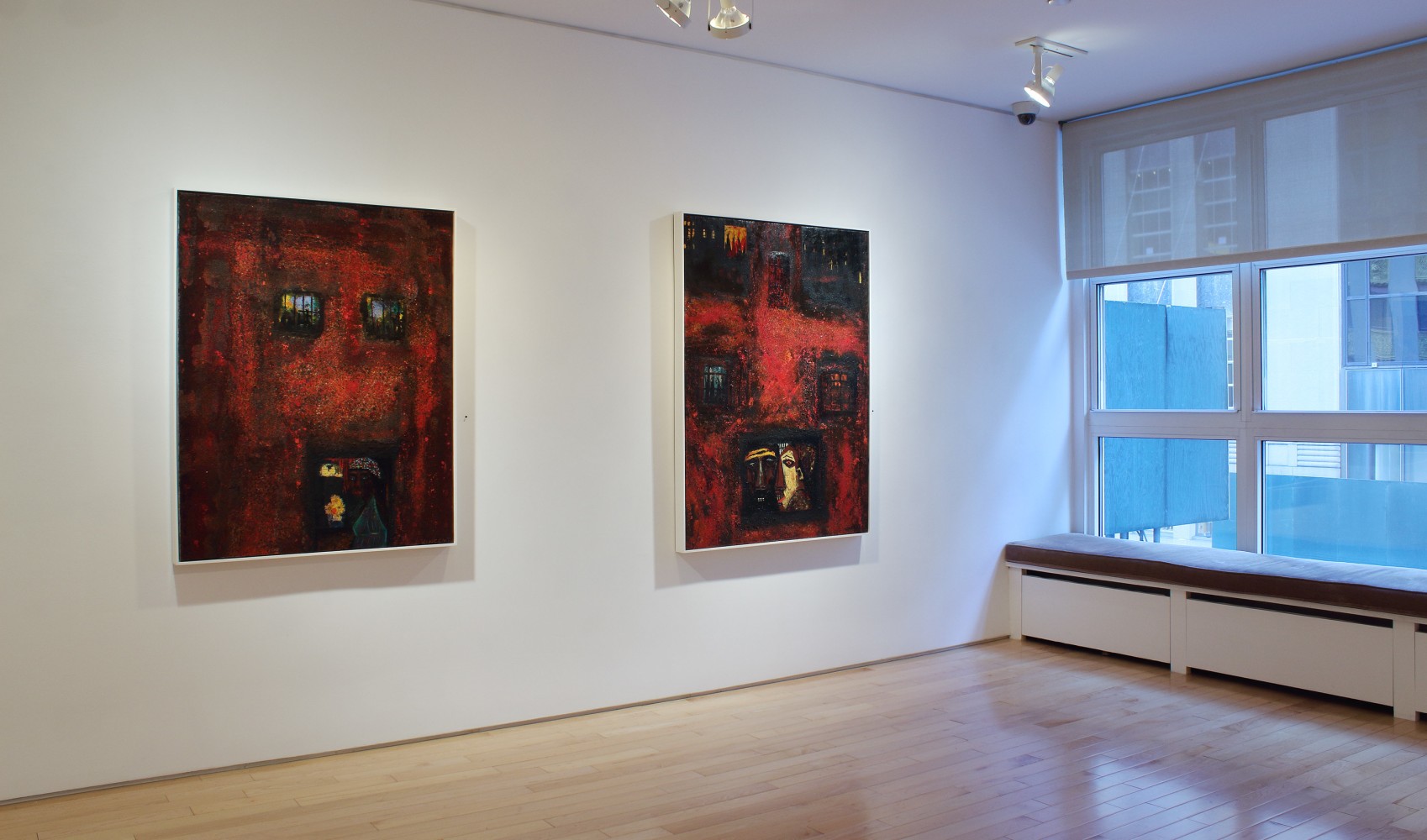 Photograph showing a view of an exhibition space, with two paintings hanging on a white wall