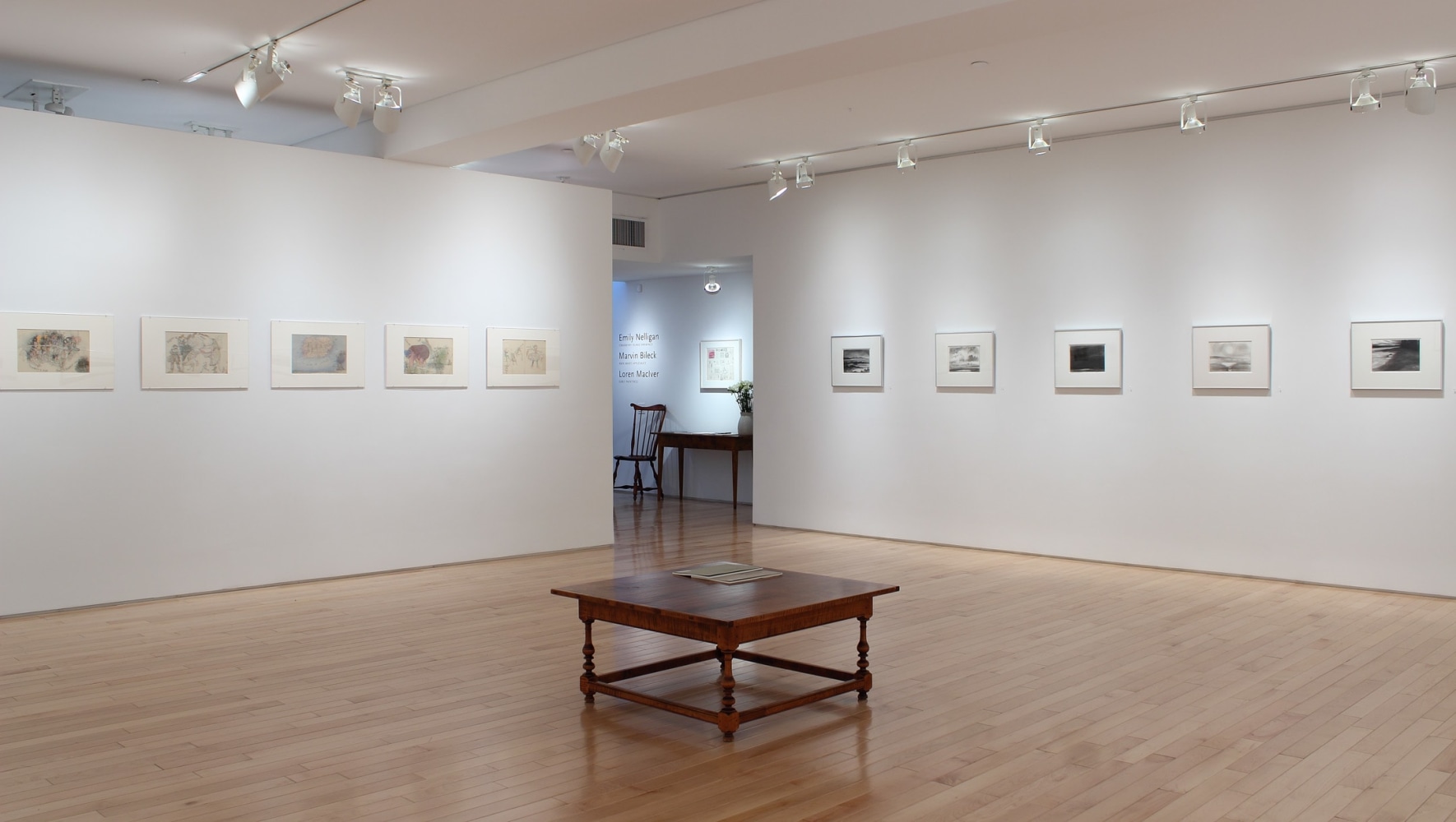 Photograph showing a corner view of an exhibition space, with ten drawings hanging on white walls.