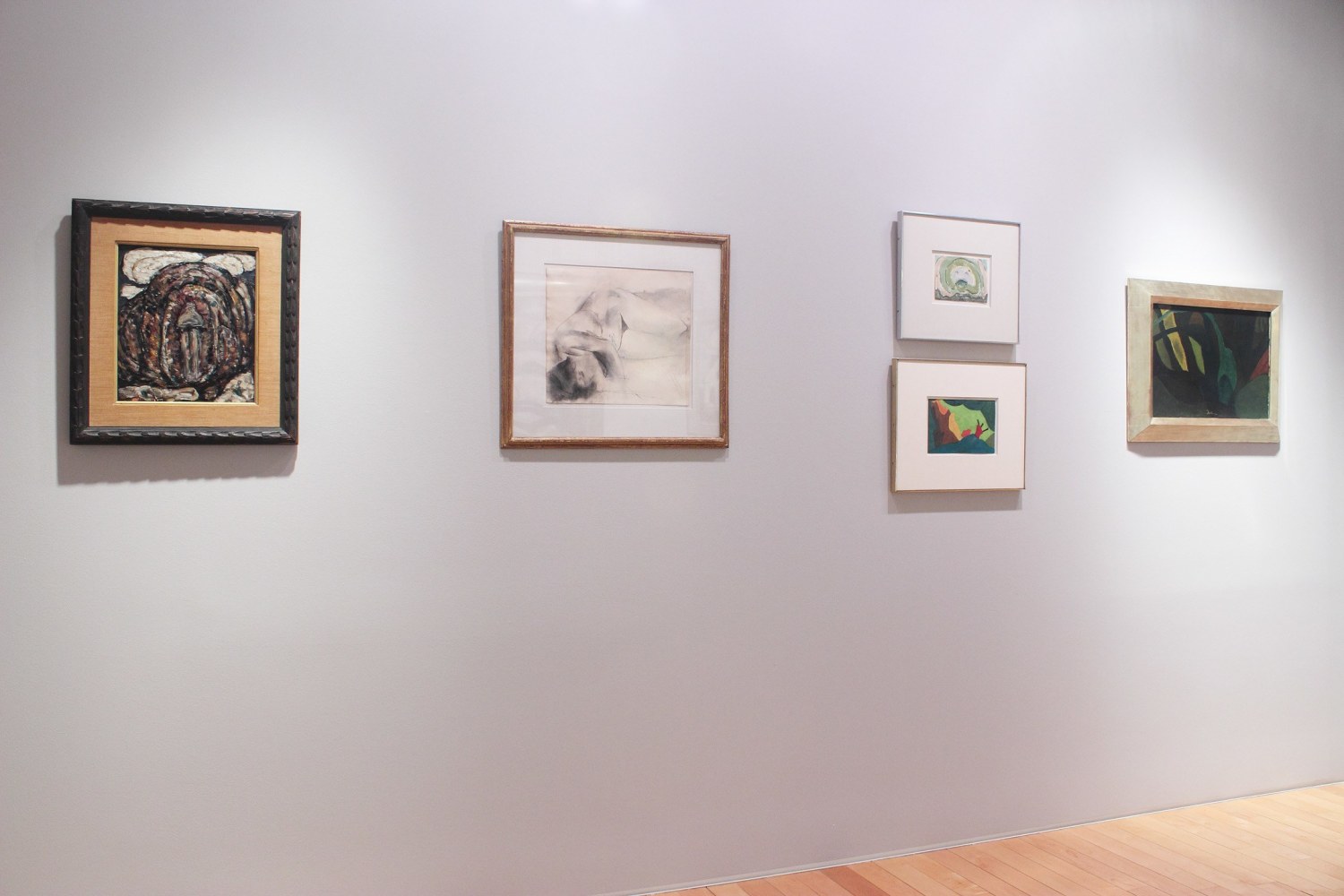 Photograph showing a view of an exhibition space with five small paintings hanging on a grey wall