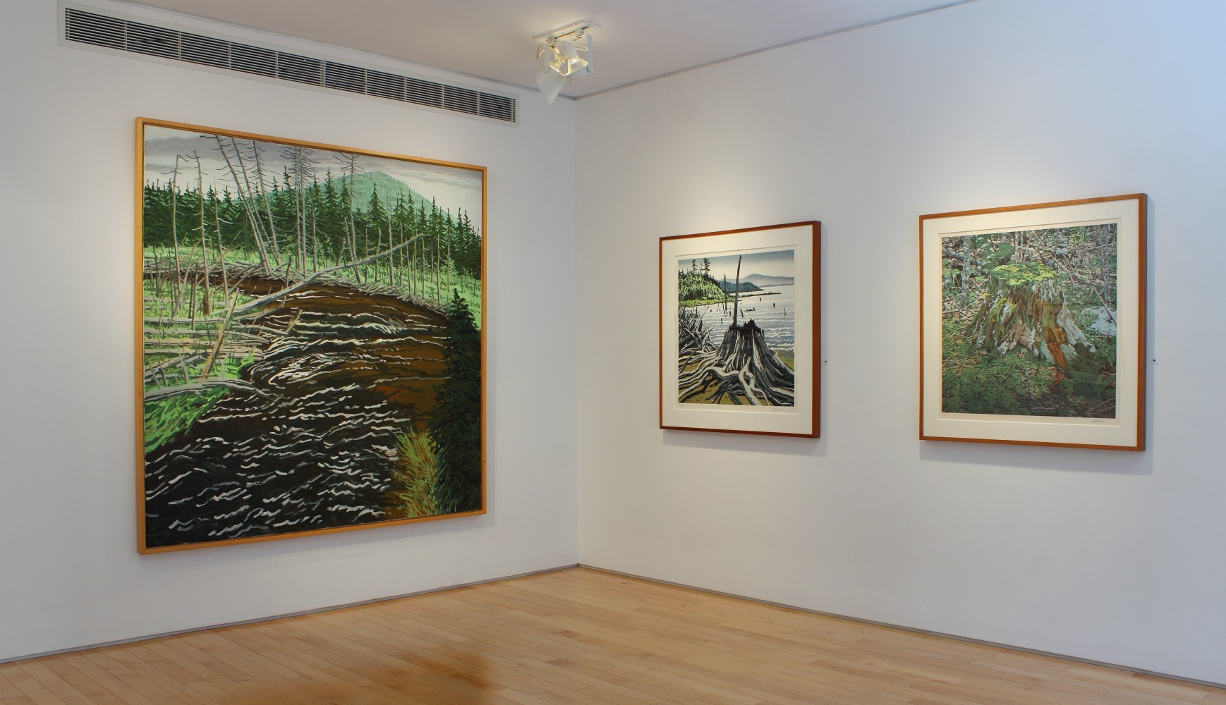 Photograph showing a corner view of an exhibition space with three paintings hanging on white walls
