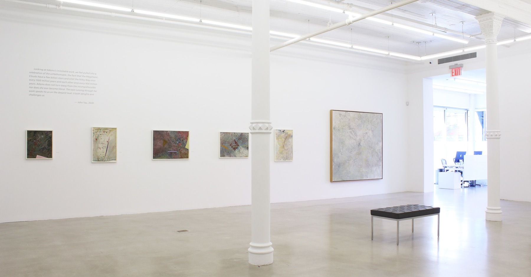 Photograph showing a view of an exhibition space, with six paintings hanging on a white wall
