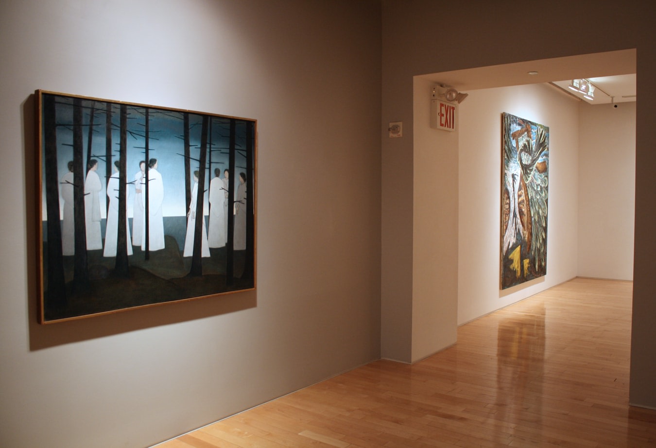Photograph showing a view of an exhibition, with two large framed paintings hanging on the walls