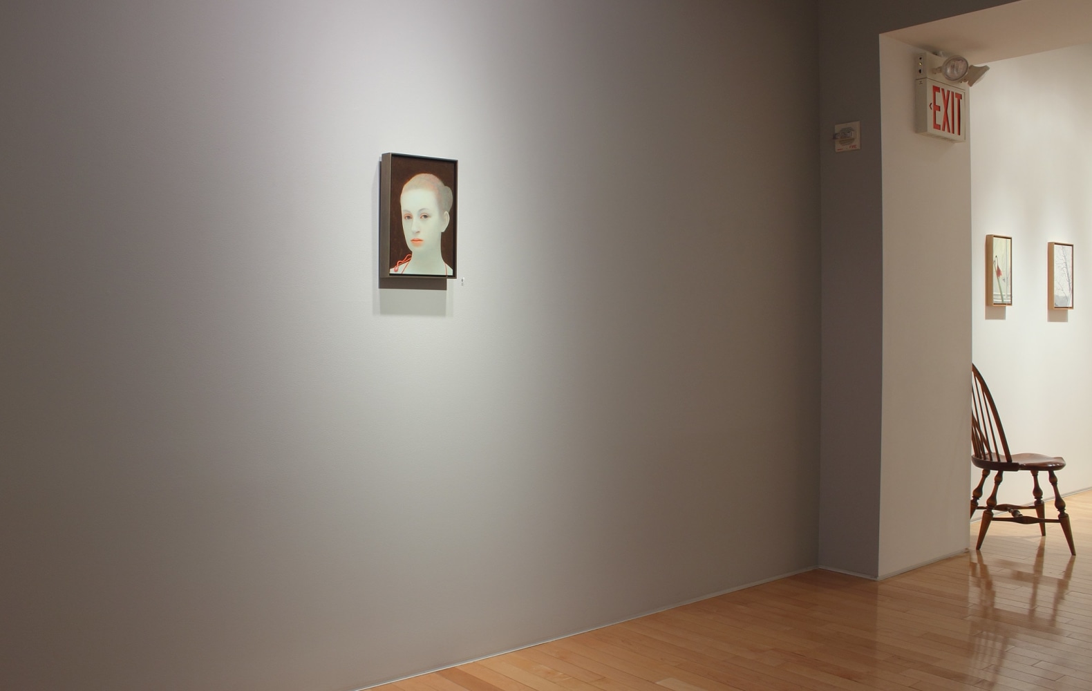 Photograph showing a view of an exhibition space, with one small painting hanging on a wall