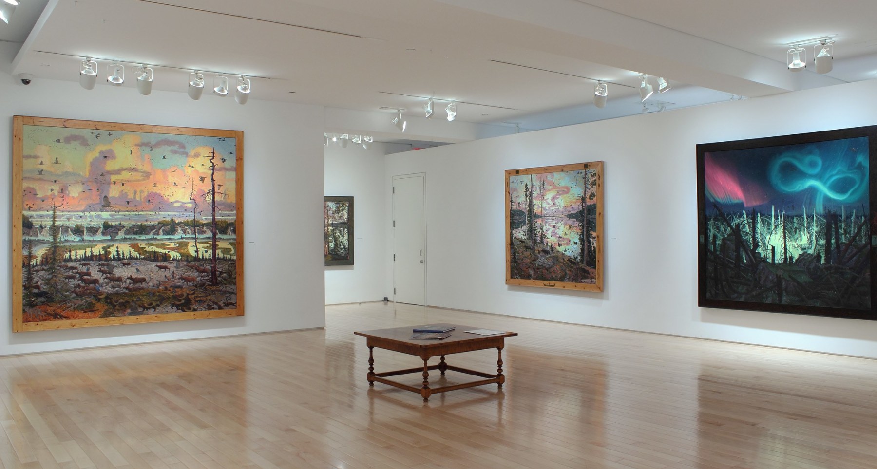 Photograph showing a corner view of an exhibition space, with four paintings hanging on white walls
