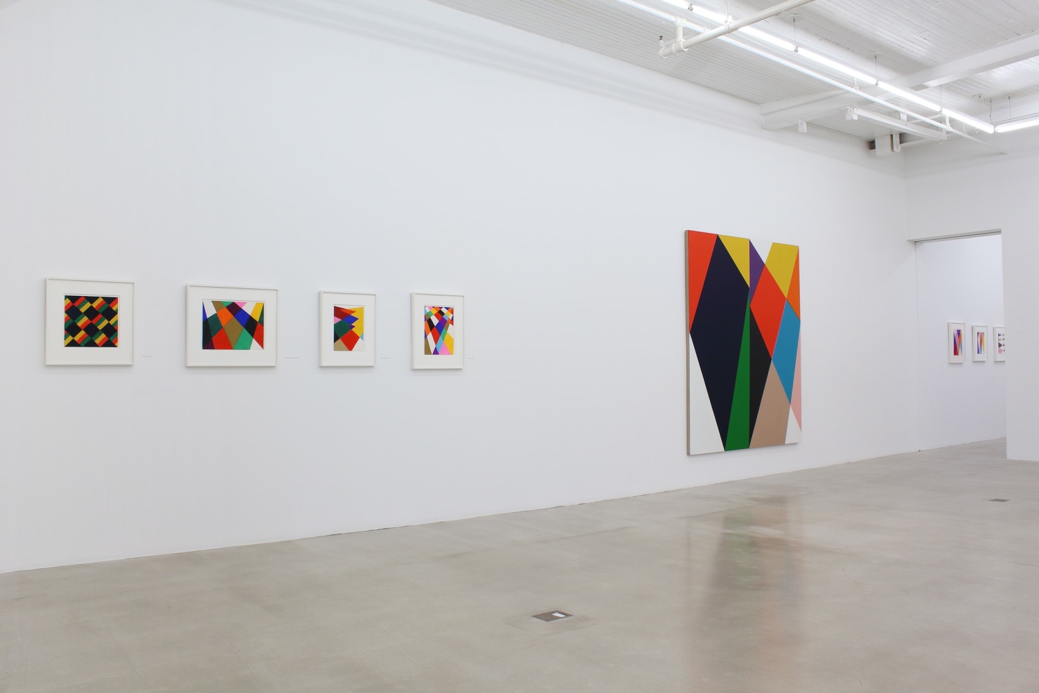 Photograph showing a view of an exhibition space, with eight paintings hanging on a white wall